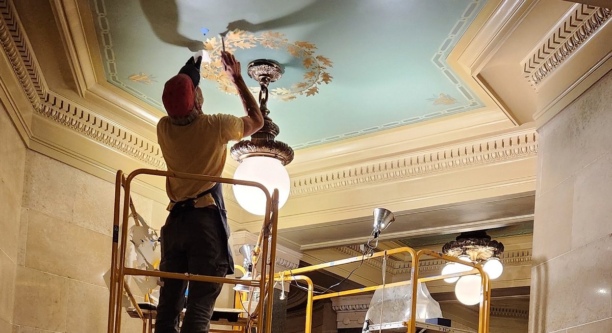 Since the major State Capitol renovation of 1988-2001, the Capitol has been meticulously maintained in its architectural glory. Here, a craftsman applies gold leaf to a ceiling panel on the Capitol’s ground floor.